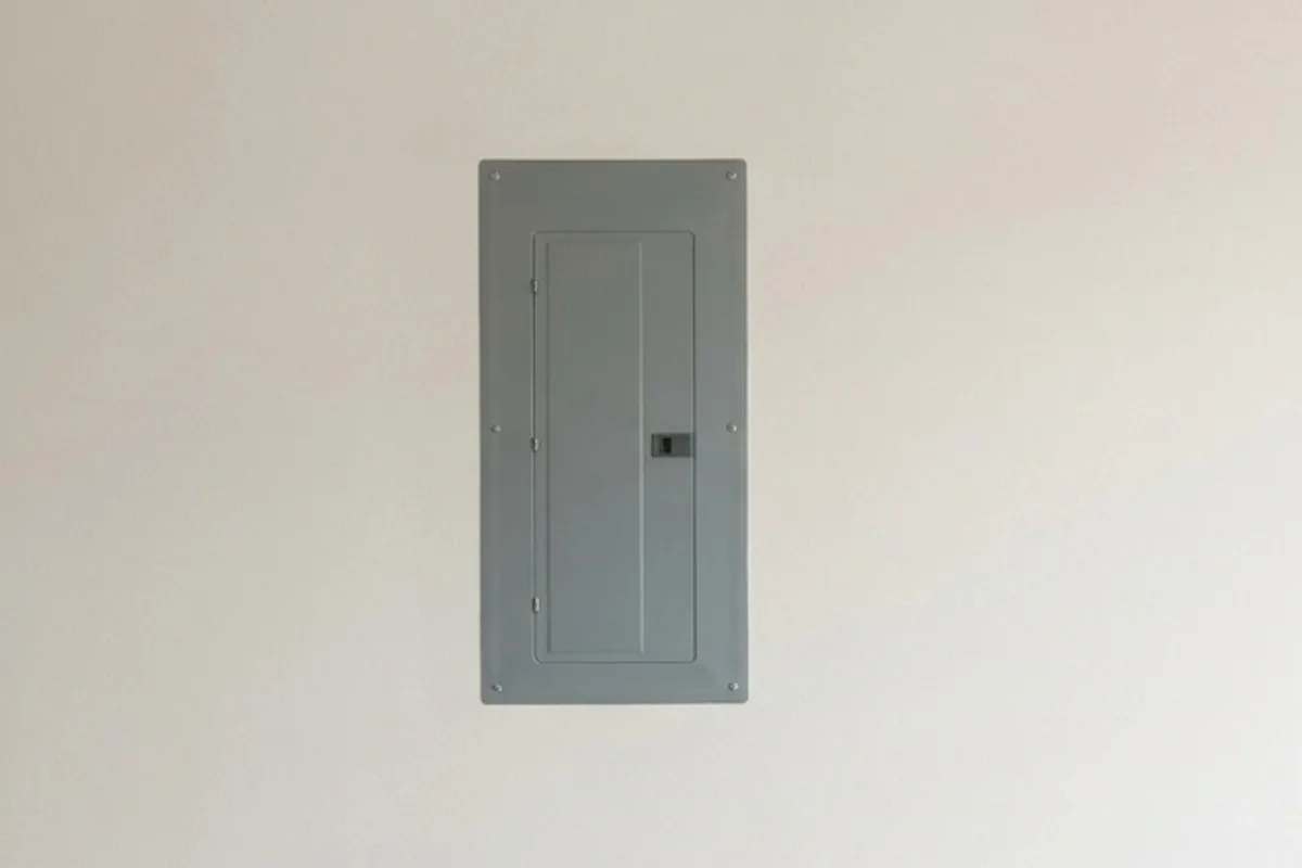 A closed residential electrical panel on a garage wall
